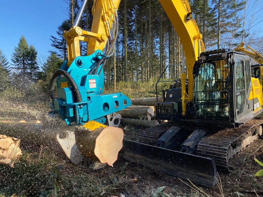 伐採現場で丸太を切断する青色のアタッチメントを備えた重機
